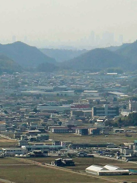 山と山の谷間からかすかに名古屋駅前のビル群が見える。右側の山にあった猿啄城が落城し、平地を近づいてくる信長軍の様子が当時もよく見えただろう＝同.jpg
